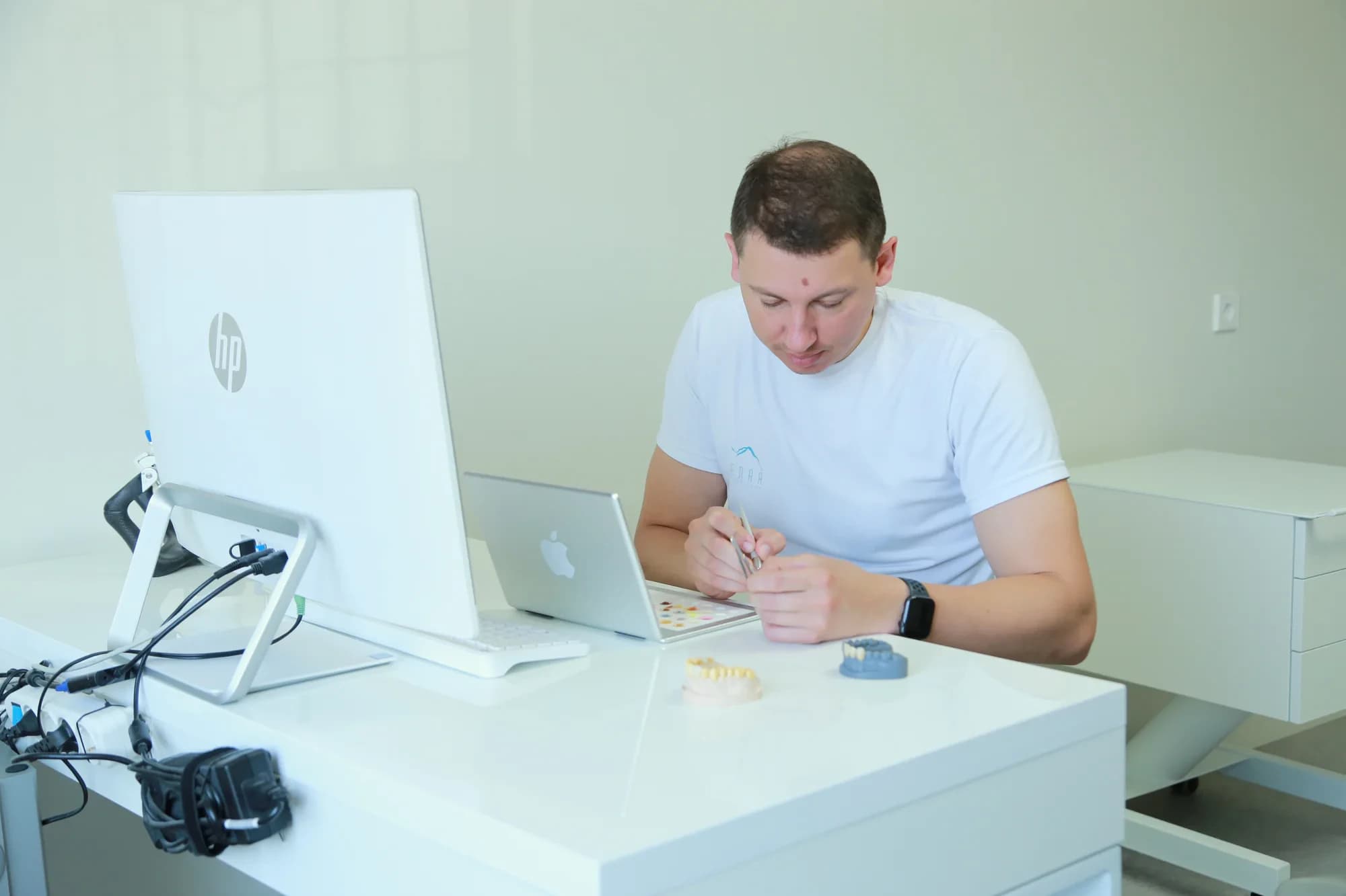 Зубной техник работает с моделью зубов за рабочим столом