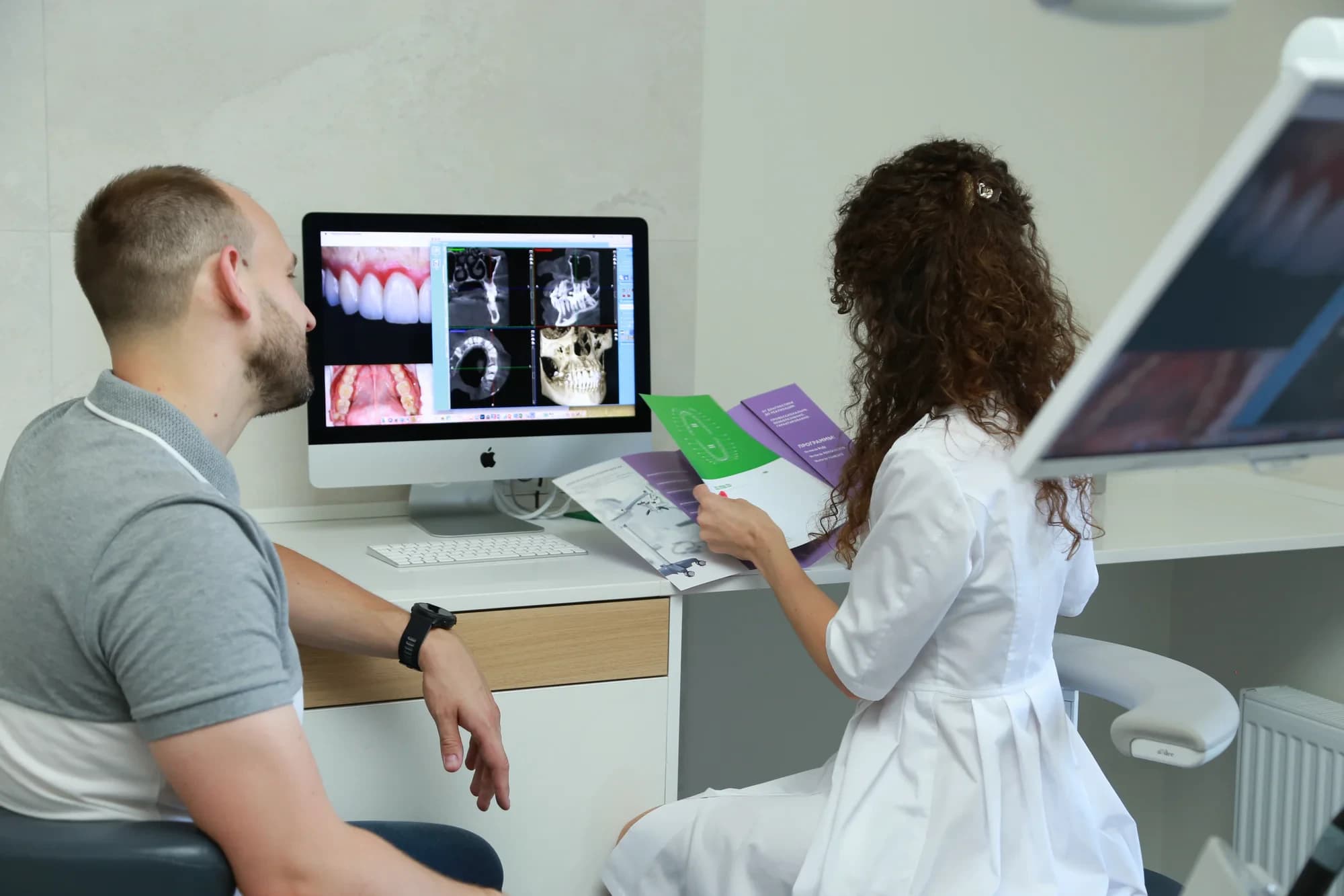 Врач показывает пациенту 3D-снимок челюсти на мониторе