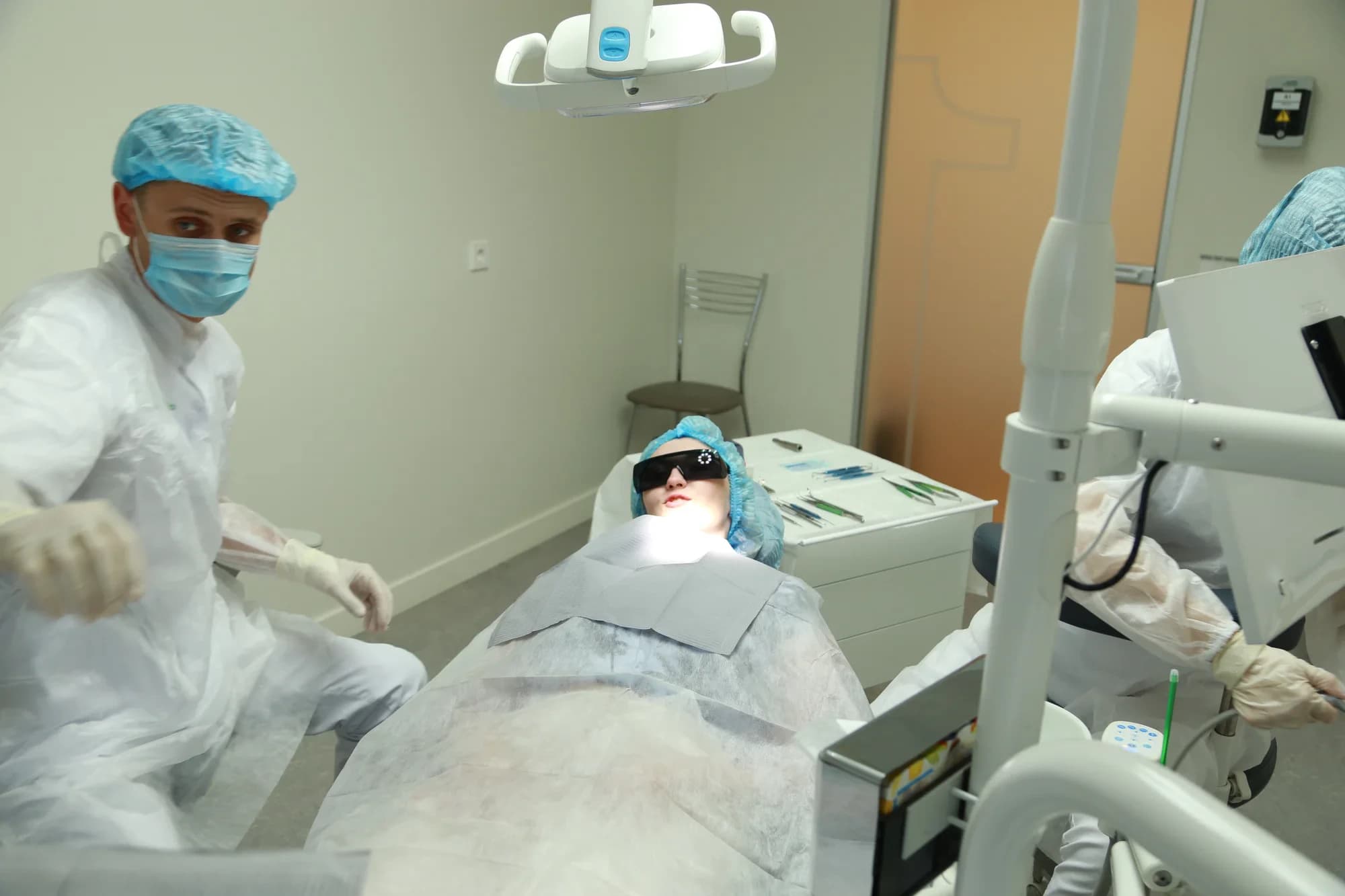 Хирург и ассистент готовят пациентку к удалению зуба